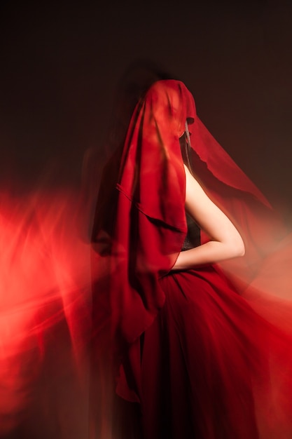 Portrait de femme méconnaissable recouverte de tissu rouge.Longue exposition