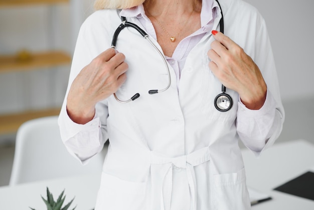 Portrait d'une femme médecin d'âge moyen porte une blouse de médecin blanche avec un stéthoscope autour du cou Médecin souriant debout dans une clinique privée