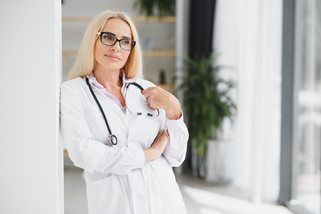 Portrait d'une femme médecin d'âge moyen porte une blouse de médecin blanche avec un stéthoscope autour du cou Médecin souriant debout dans une clinique privée