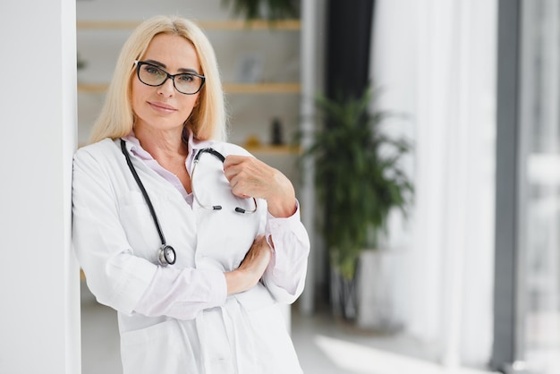 Portrait d'une femme médecin d'âge moyen porte une blouse de médecin blanche avec un stéthoscope autour du cou Médecin souriant debout dans une clinique privée