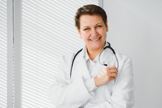 Portrait d'une femme médecin d'âge moyen porte une blouse de médecin blanche avec un stéthoscope autour du cou