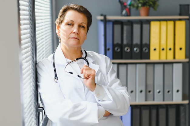 Portrait d'une femme médecin d'âge moyen porte une blouse de médecin blanche avec un stéthoscope autour du cou