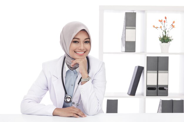 Portrait de femme médecin asiatique avec stéthoscope assis et souriant au bureau