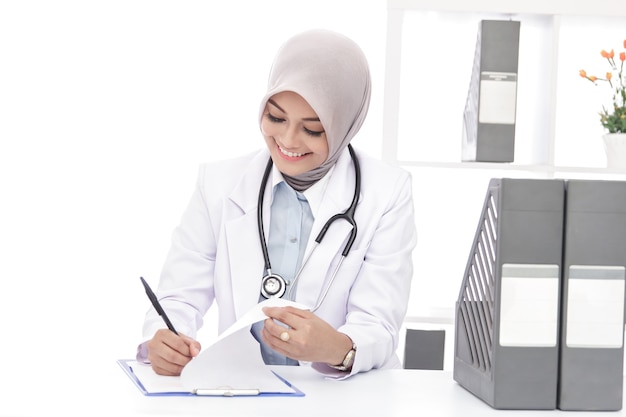 Portrait de femme médecin asiatique avec stéthoscope écrit une note au bureau