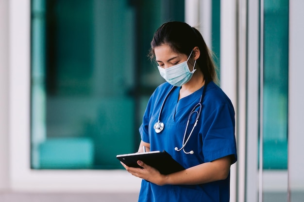 Portrait d'une femme médecin asiatique avec stéthoscope écrivant sur le presse-papiers