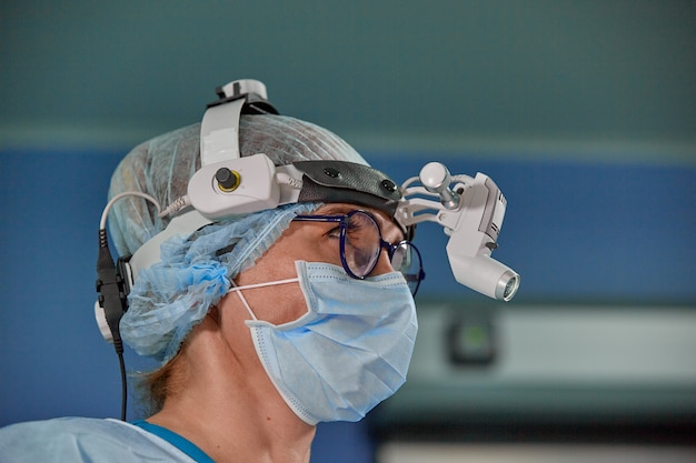 Portrait de femme médecin chirurgien portant un masque de protection et un chapeau pendant l'opération