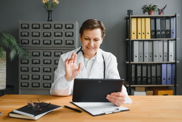 Portrait d'une femme médecin conseillant une patiente par appel vidéo Médecin professionnel en blouse blanche faisant des gestes et expliquant le déroulement du traitement assis au bureau pendant la consultation en ligne