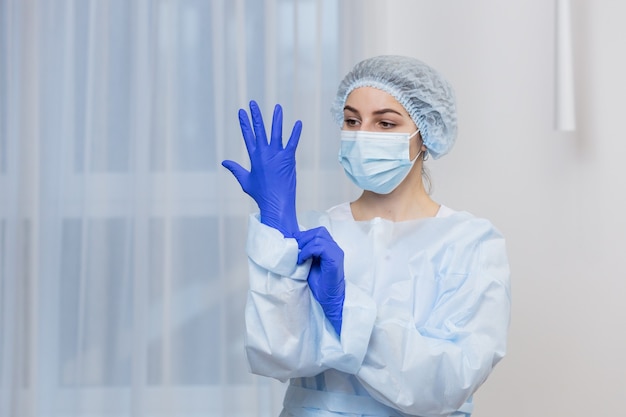 Portrait d'une femme médecin, dans un costume bleu de protection, et un masque médical sur son visage