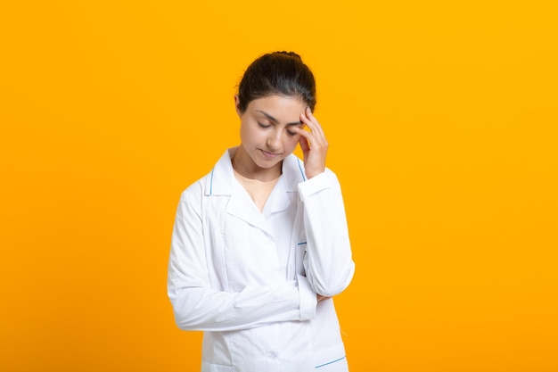 Portrait de femme médecin indien en robe médicale blanche isolée sur fond jaune