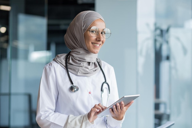 Portrait d'une femme médecin musulmane dans un hijab avec une tablette dans ses mains le médecin travaille dans le