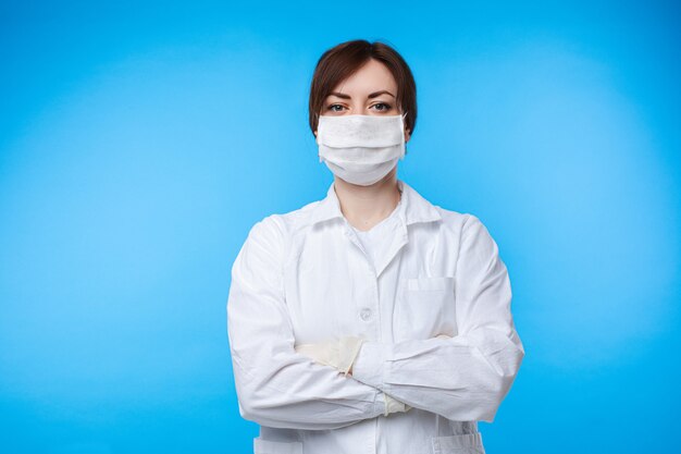 Portrait de femme médecin professionnel en uniforme blanc et masque de protection posant