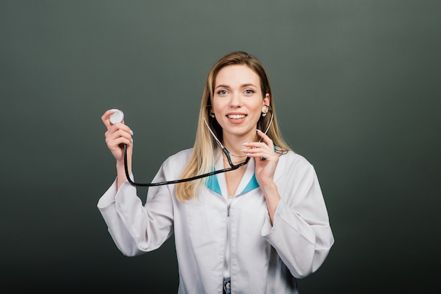 Portrait de femme médecin avec stéthoscope sur gris