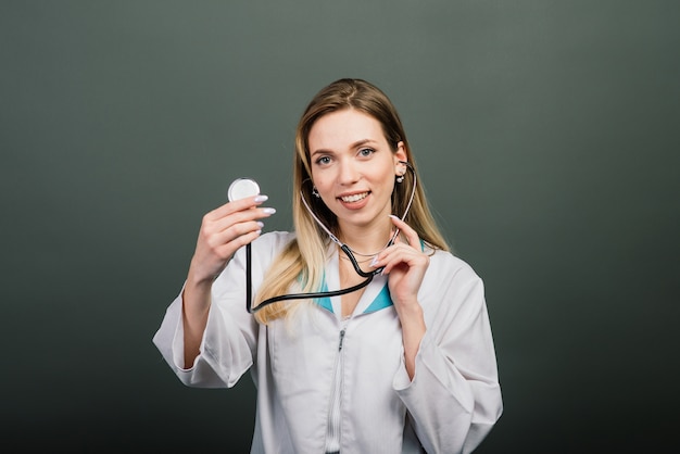 Portrait de femme médecin avec stéthoscope regardant la caméra sur fond gris