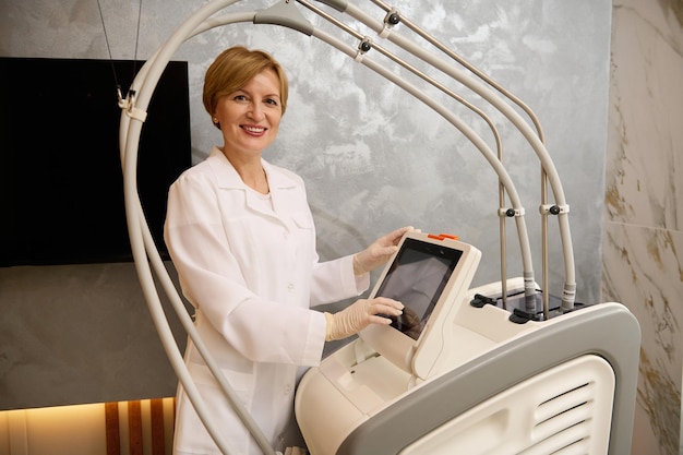 Portrait d'une femme médecin travaillant sur des programmes de réglage d'équipement médical à ultrasons avant de traiter un patient dans la clinique spécialisée en cosmétologie matérielle