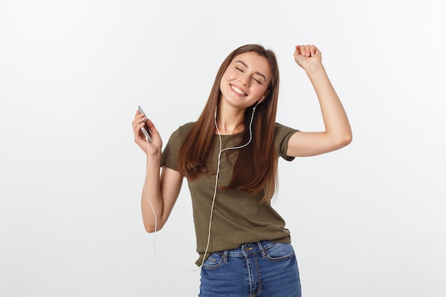 Portrait d'une femme mignonne joyeuse, écouter de la musique dans les écouteurs et danser isolé sur un blanc.