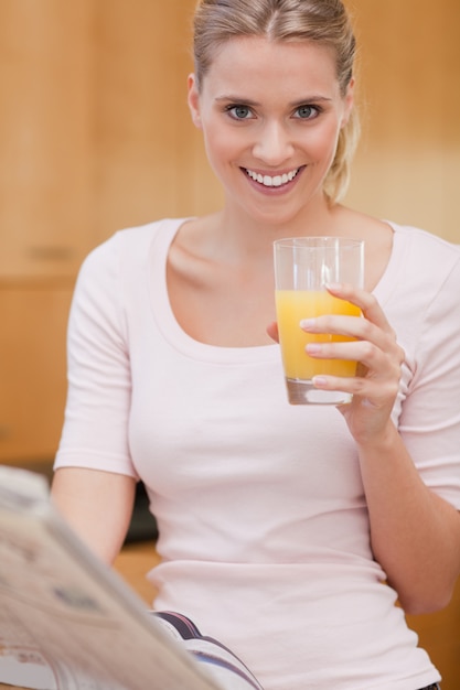 Portrait d&#39;une femme mignonne lisant les nouvelles tout en buvant du jus