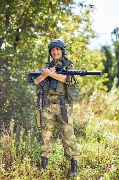 Portrait de femme militaire confiante avec une arme à feu en forêt