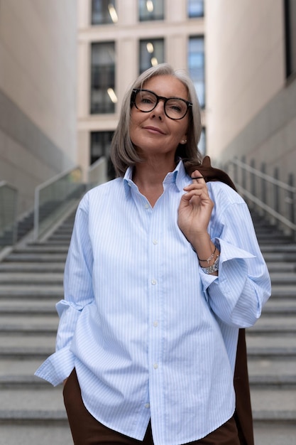 Portrait d'une femme mince aux cheveux gris modèle d'âge mûr vêtue d'une chemise bleu clair debout