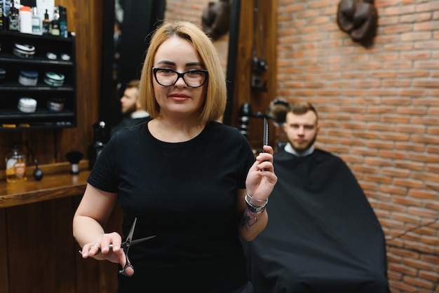 Portrait de femme de mode coiffeur coiffeur avec des ciseaux à la main dans le salon de coiffure