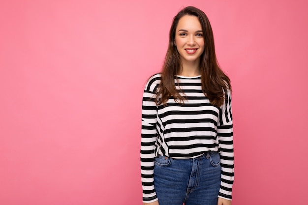 Portrait de femme à la mode gaie positive dans des vêtements décontractés isolés sur fond rose avec