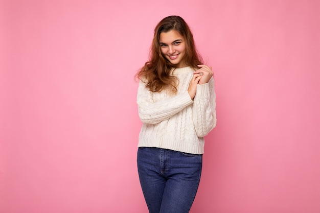 Portrait de femme à la mode joyeuse positive en tenues de soirée regardant la caméra isolée sur une surface rose avec copie espace