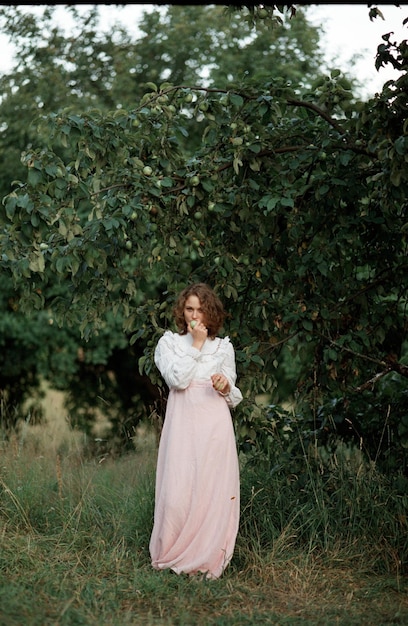 Photo portrait d'une femme mordant un fruit alors qu'elle se tient contre une plante