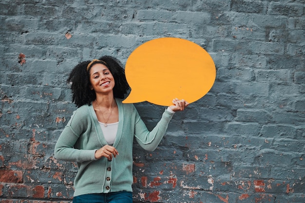 Portrait de femme et mur de briques avec bulle de dialogue pour une publicité heureuse sur les médias sociaux ou l'opinion Communication marketing ou voix de marque d'une femme noire avec sourire de joie et maquette de signe orange