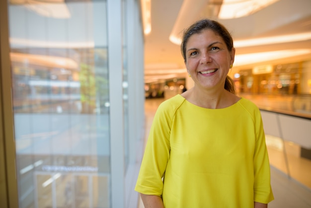 Portrait de femme mûre heureuse souriant à l'intérieur du centre commercial