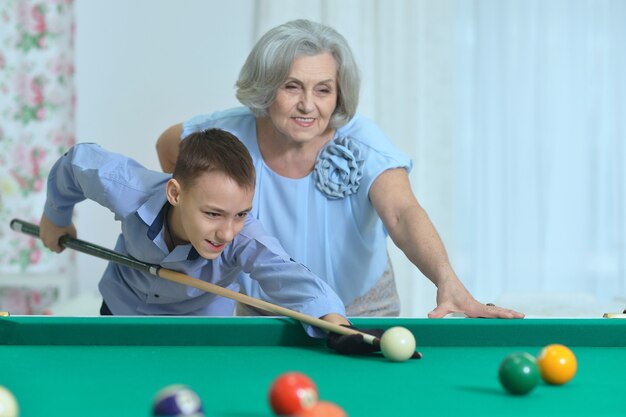 Portrait d'une femme mûre jouant au billard avec petit-fils