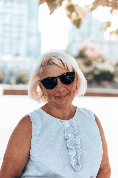 Portrait de femme mûre satisfaite positive blonde adulte à lunettes de soleil souriant