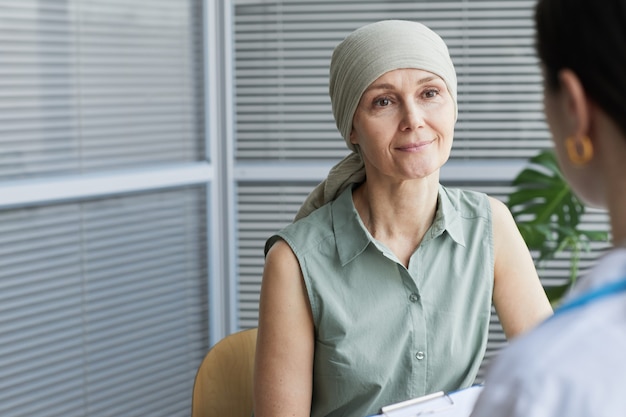 Photo portrait d'une femme mûre souriante en parlant à une femme médecin lors d'une consultation en clinique, espace de copie