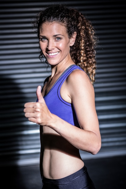 Portrait de femme musclée souriante regardant la caméra avec le pouce vers le haut