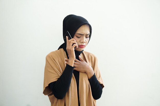 Portrait d'une femme musulmane asiatique triste portant le hijab faisant un appel avec un téléphone portable