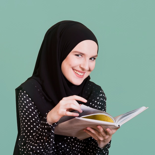 Photo portrait d'une femme musulmane heureuse, tenant le livre à la main