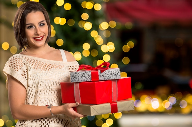 Portrait de femme de Noël tenant le cadeau de Noël. Femme heureuse souriante sur les lumières de Noël bokeh