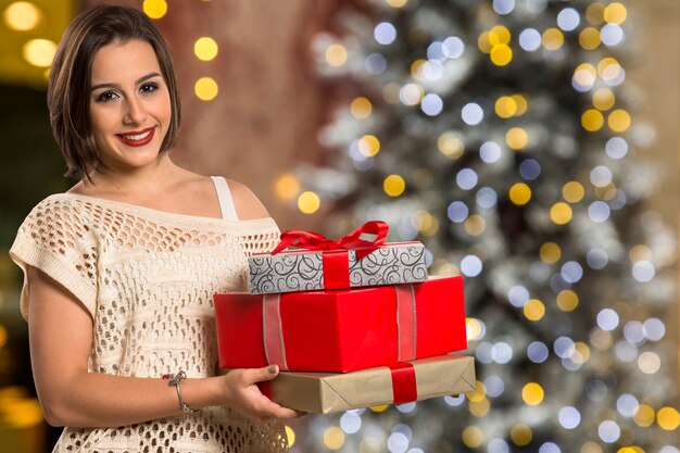 Portrait de femme de Noël tenant le cadeau de Noël. Femme heureuse souriante sur les lumières de Noël bokeh