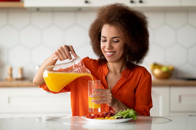 Portrait d'une femme noire souriante prenant un petit-déjeuner sain dans la cuisine à la maison