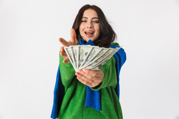 Portrait de femme optimiste dans des vêtements décontractés tenant fan d'argent dollar, debout isolé sur blanc