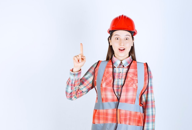 Portrait de femme ouvrier du bâtiment pointant sur fond blanc.