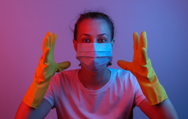 Portrait de femme panique dans un masque médical et des gants. Néon dégradé bleu rose. Protection contre la pandémie covid-19