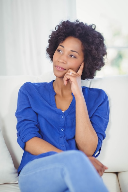 Portrait de femme pensive sur le canapé à la maison