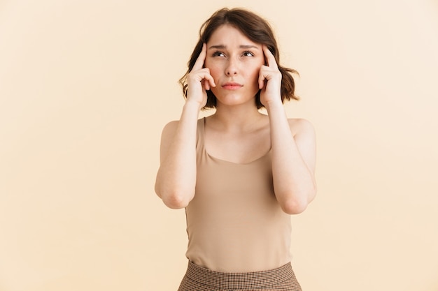 Portrait de femme perplexe concentrée 20s vêtue de vêtements décontractés fronçant les sourcils et touchant ses tempes isolées