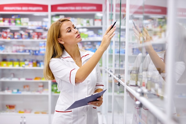 Portrait femme pharmacien écrit sur le presse-papiers à la pharmacie