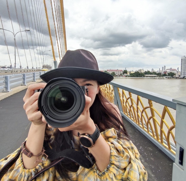 Photo portrait femme d'un photographe couvrant son visage avec un appareil photo