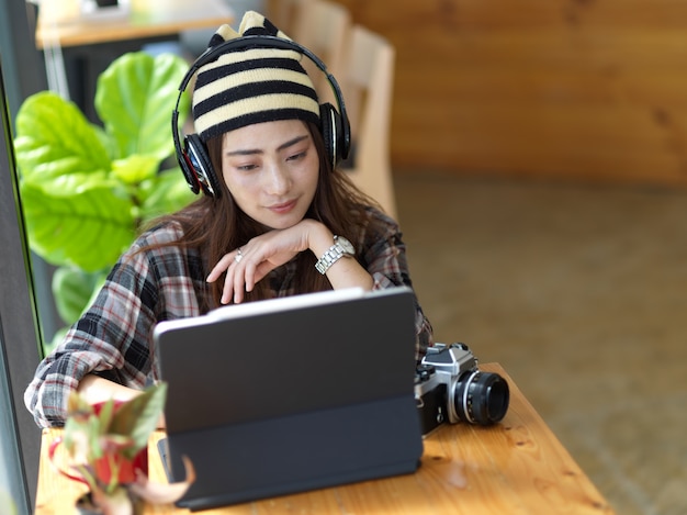 Portrait de femme photographe travaillant avec tablette numérique et casque sur table en bois