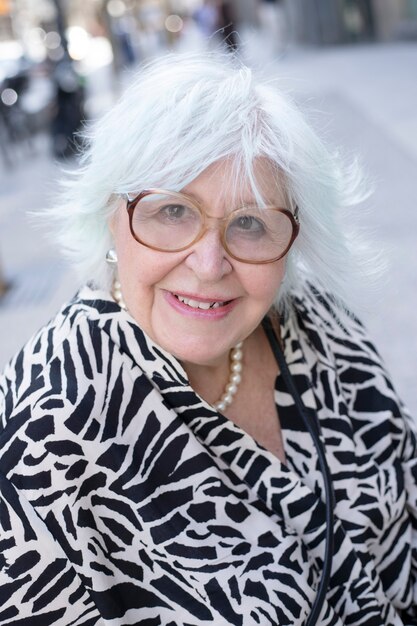 Portrait d'une femme plus âgée aux cheveux gris et sourire regardant la caméra à l'extérieur