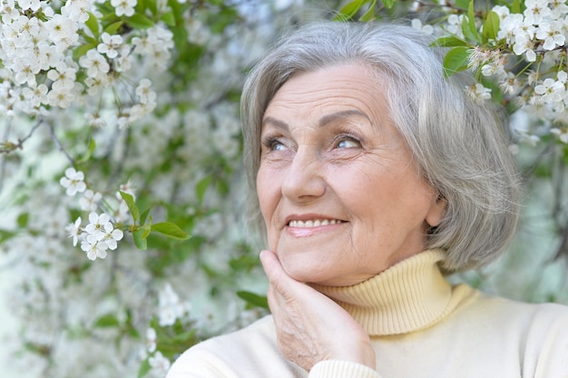 Portrait de femme plus âgée avec des fleurs dans le parc