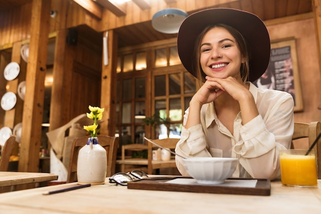 Portrait De Femme Portant Chapeau De Boire Du Jus D'orange, Alors Qu'il était Assis Au Restaurant