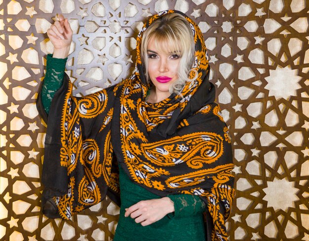 Photo portrait d'une femme portant un foulard debout contre le mur