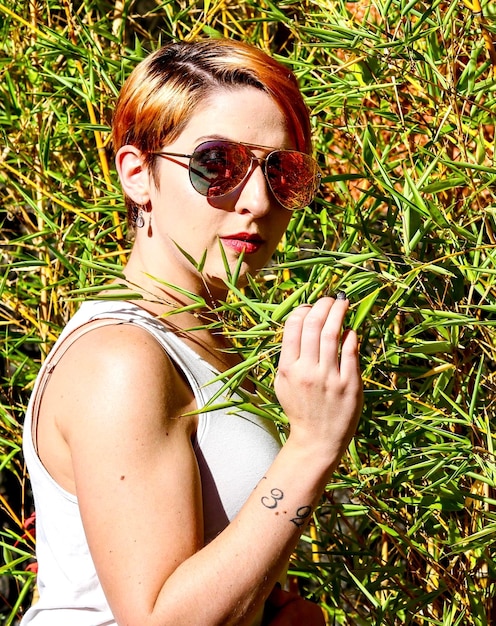 Portrait d'une femme portant des lunettes de soleil par des plantes